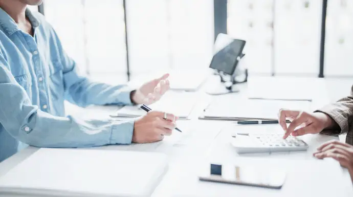 Asesoría fiscal con dos profesionales revisando cálculos y documentación financiera