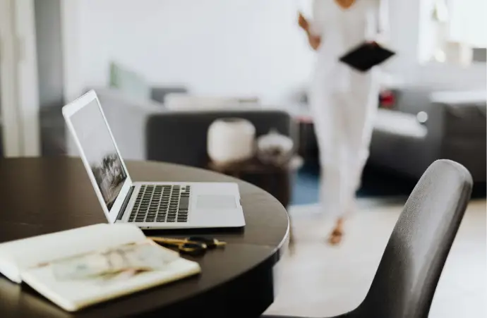 Mujer trabajando en asesoría laboral, llevando documentos mientras se dirige al ordenador