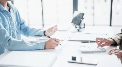 Asesoría fiscal con dos profesionales revisando cálculos y documentación financiera