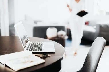 Mujer trabajando en asesoría laboral, llevando documentos mientras se dirige al ordenador